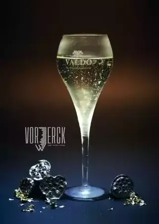 Ein Glas prickelnder Sekt mit Golddeko und dunklem Hintergrund für festliche Anlässe.