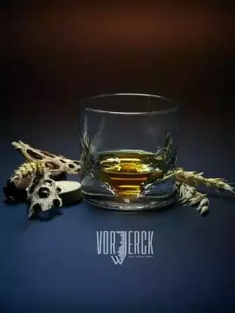 Whiskyglas mit goldenem Whisky, umgeben von Knochen, auf dunklem Hintergrund, Vorjerck-Logo.