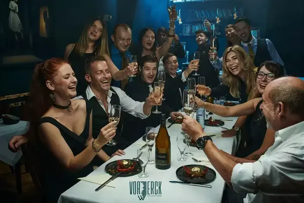 Gruppe feiert fröhlich in eleganter Restaurant-Atmosphäre mit Sekt und Abendessen.