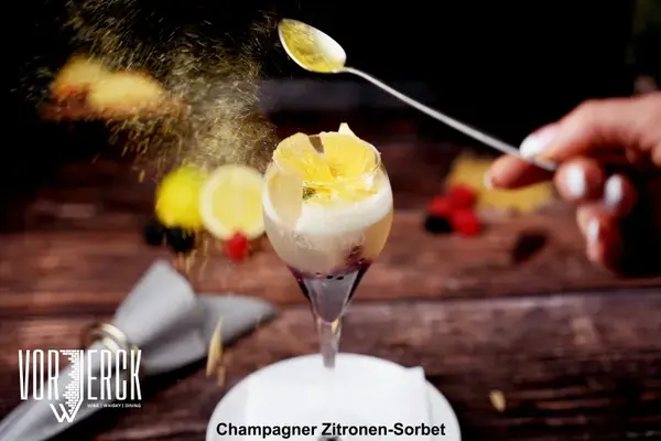 Ein Glas mit Champagner Zitronen-Sorbet wird kunstvoll mit Puderzucker bestäubt.