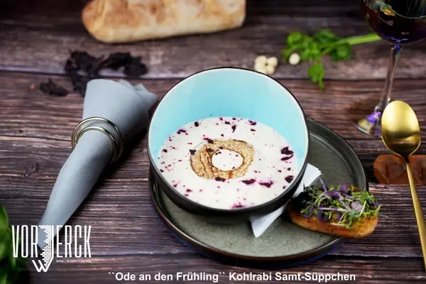 Cremige Kohlrabi-Samtsuppe mit Brot und Kräutern, serviert auf rustikalem Holztisch.