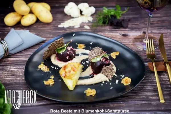 Rote Beete auf cremigem Blumenkohlpüree mit Kartoffelbeilage und Dekoration serviert.