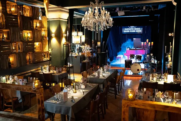 Stimmungsvolles Restaurant mit festlich gedeckten Tischen und Bühne für Live-Musik.