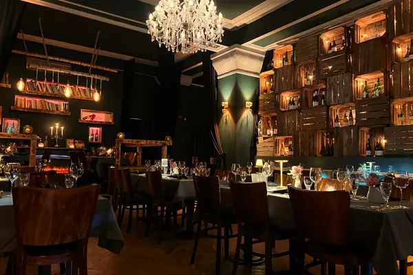 Gemütliches Restaurant mit Kronleuchter, Weinregalen aus Holzkisten und elegant gedeckten Tischen.