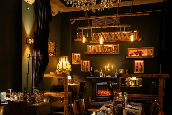 Gemütliches Restaurant mit stimmungsvoller Beleuchtung, Kamin, Büchern und gedeckten Tischen.