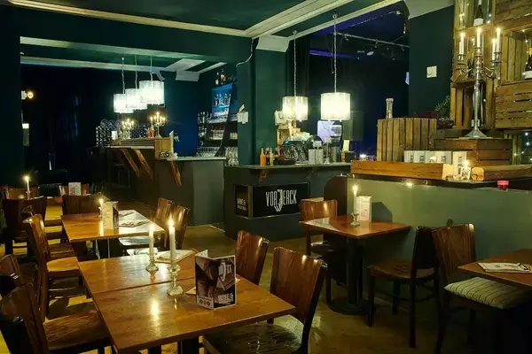 Gemütliches Café mit Holztischen, Kerzenlicht und moderner Bar im stilvollen Ambiente.