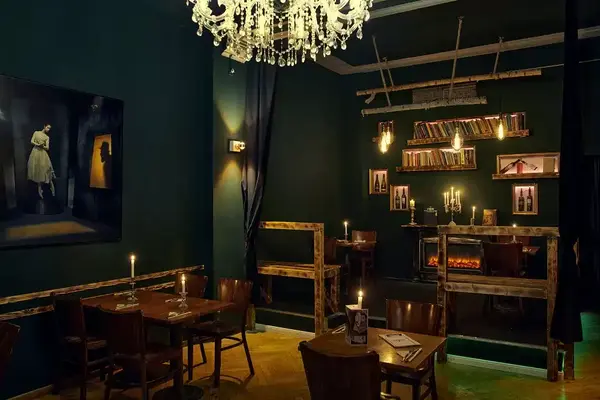 Gemütliches Restaurant mit Kerzenlicht, Bücherregalen, Kamin und stilvoller Dekoration.
