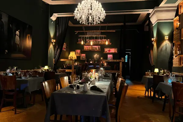 Stilvolles Restaurant mit dunklem Ambiente, Kronleuchter und elegant gedeckten Tischen.