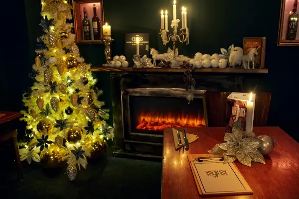 Gemütlich dekoriertes Restaurant mit festlich geschmücktem Weihnachtsbaum und Kaminfeuer.